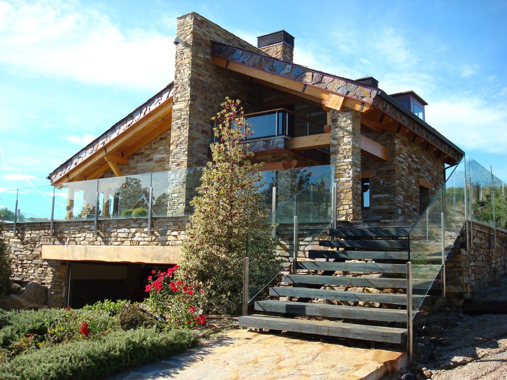 exterior de casa rural hecha de piedra y cristal con un diseño moderno